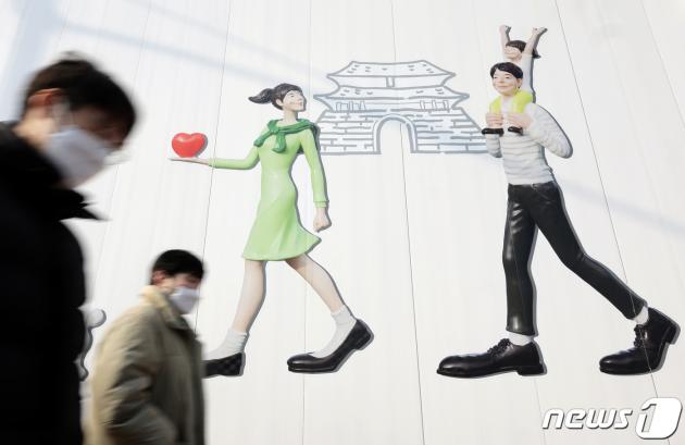 서울 도심의 공사장 가림막에 그려진 행복한 가족 그림 앞으로 시민들이 지나고 있다. /뉴스1 ⓒ News1 박정호 기자